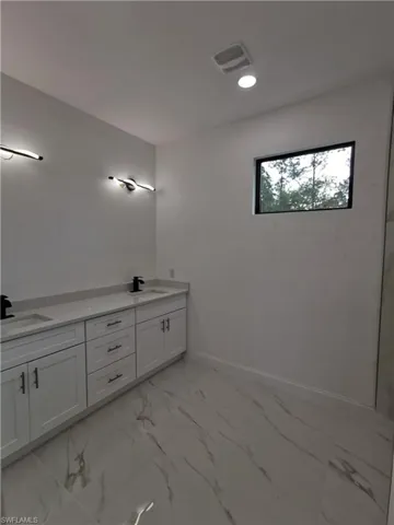 Bathroom featuring light marble finish floors, double vanity, and recessed lighting