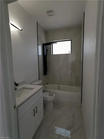 Full bathroom featuring vanity, a combined bath / shower with marble appearance, and light marble finish flooring