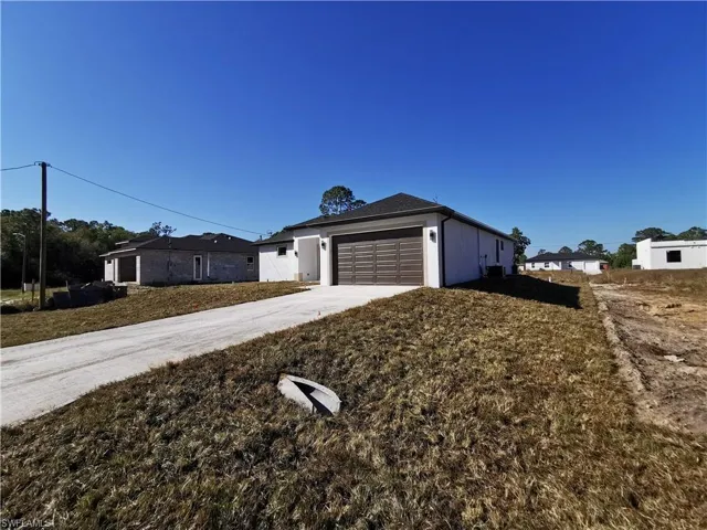 View of front of house featuring driveway, an attached garage, and a front lawn