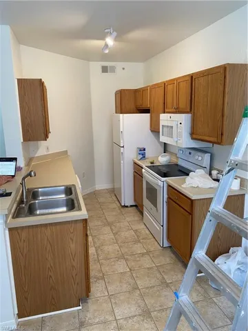 Kitchen featuring light tile patterned flooring, stove, sink, and refrigerator