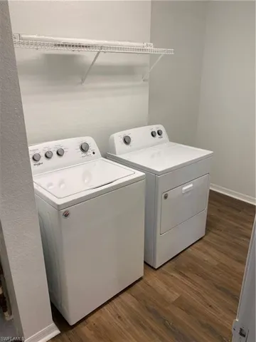 Washroom with separate washer and dryer and dark hardwood / wood-style flooring