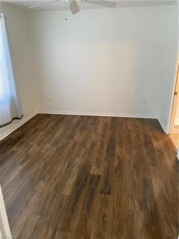 Empty room with dark hardwood / wood-style flooring and ceiling fan