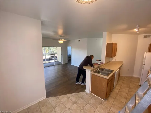 Kitchen featuring white fridge, dishwashing machine, light tile patterned floors, ceiling fan, and sink