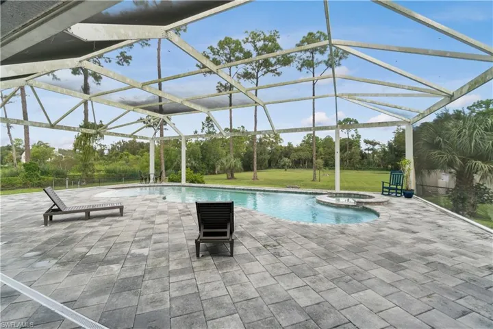 View of swimming pool with a patio area, a pool with connected hot tub, and glass enclosure