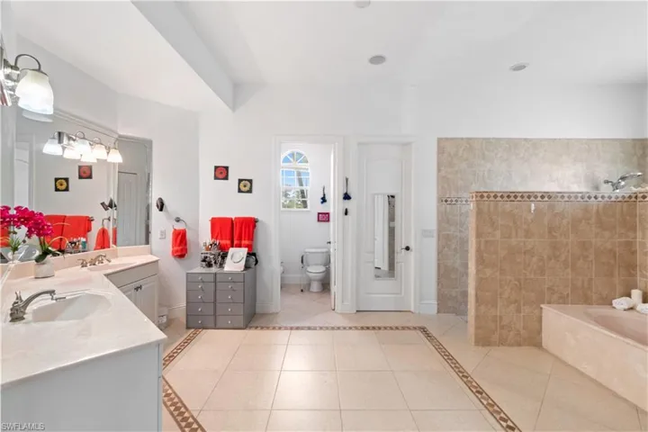 Bathroom featuring toilet, tile patterned flooring, vanity, and a bath