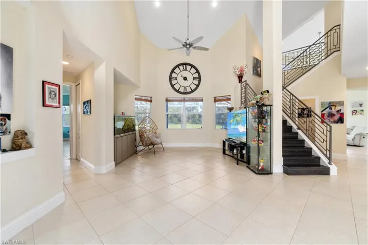 Foyer featuring light tile patterned floors, baseboards, a high ceiling, and stairway