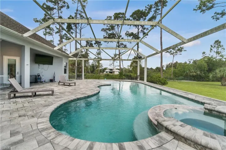 View of pool featuring a yard, a lanai, a patio area, and a pool with connected hot tub