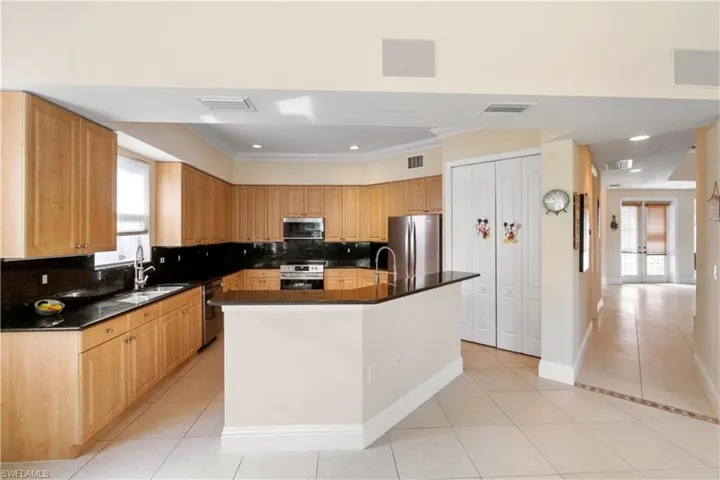 Kitchen featuring dark countertops, visible vents, appliances with stainless steel finishes, light tile patterned flooring, and a sink