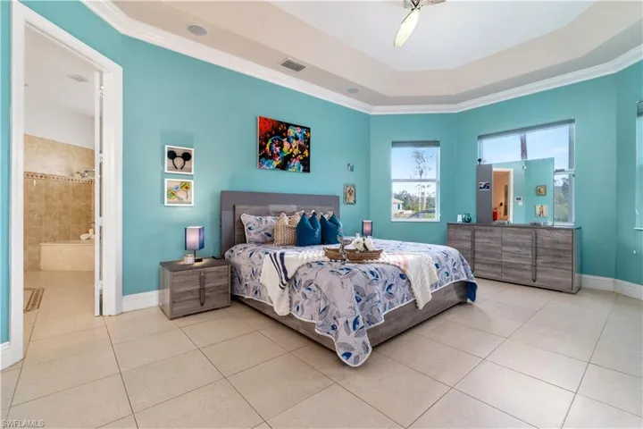 Bedroom with crown molding, a raised ceiling, visible vents, baseboards, and tile patterned floors