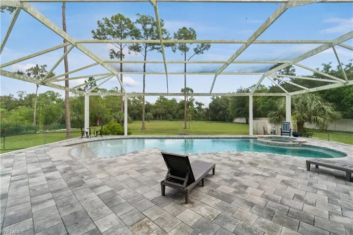 View of pool with a yard, a patio, a lanai, and a pool with connected hot tub