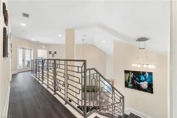 Corridor with baseboards, visible vents, lofted ceiling, dark wood-style floors, and french doors