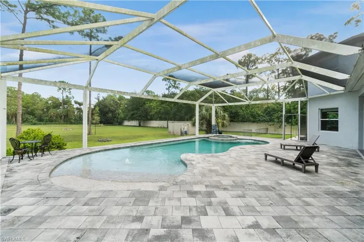 View of swimming pool with a yard, a patio area, and a lanai