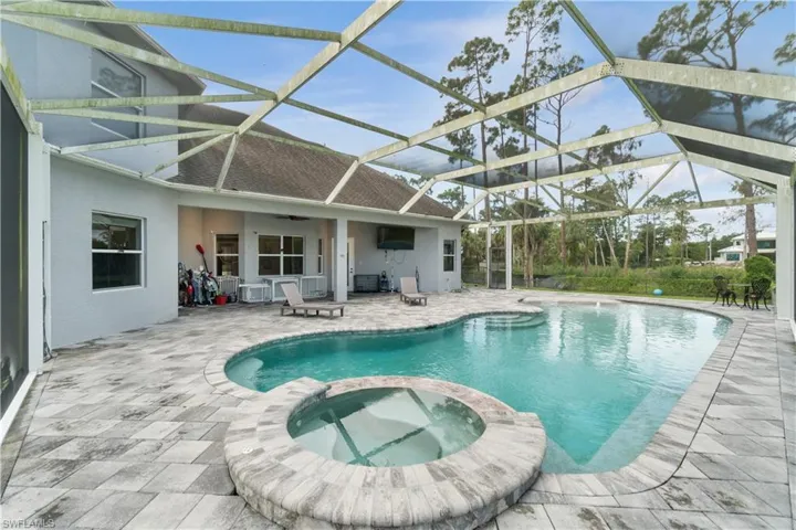 View of pool featuring a lanai, a patio area, and a pool with connected hot tub