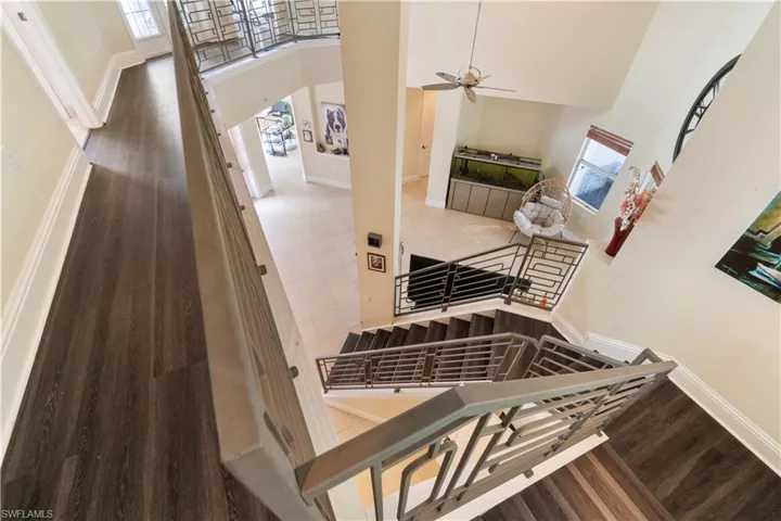 Staircase featuring a towering ceiling, baseboards, and wood finished floors