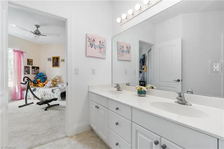 Full bath with double vanity, ensuite bath, a sink, and tile patterned floors