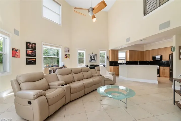 Living room featuring a ceiling fan, visible vents, baseboards, and light tile patterned floors