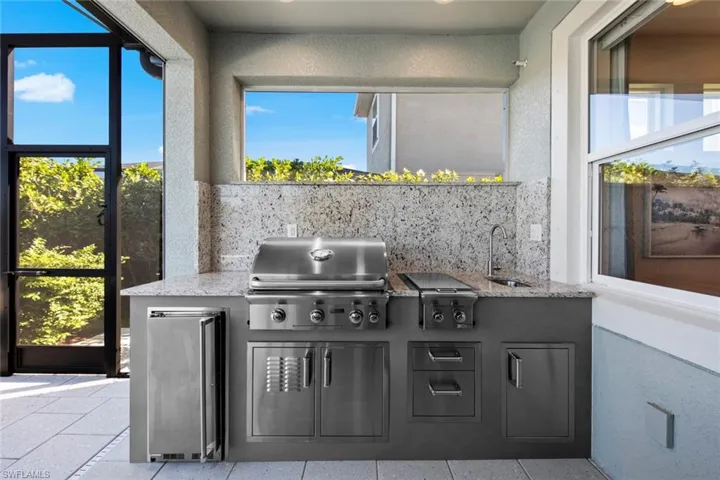 OUTDOOR KITCHEN with refrigerator, grill, side burner, sink, under counter storage, granite counter and backsplash. (September 2021)