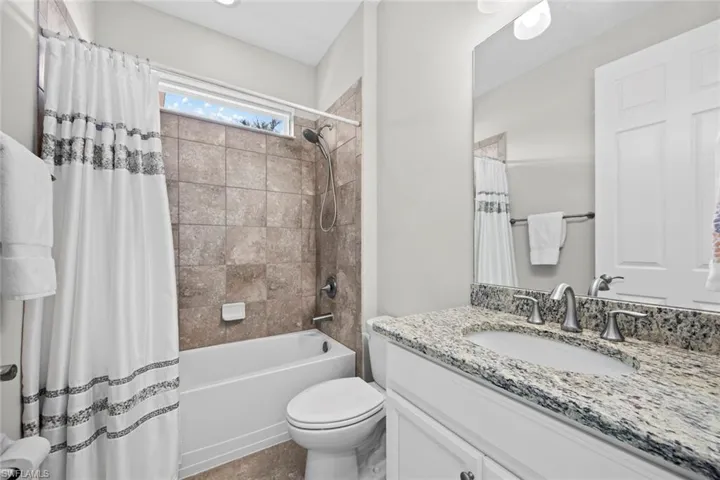 A full bath with window, tile floor, comfort height vanity with granite countertop, tub/shower with tile wall surround, and new DETACHABLE MAGNETIC SHOWER HEAD (February 2023) is conveniently located between bedroom 2 and bedroom 3.