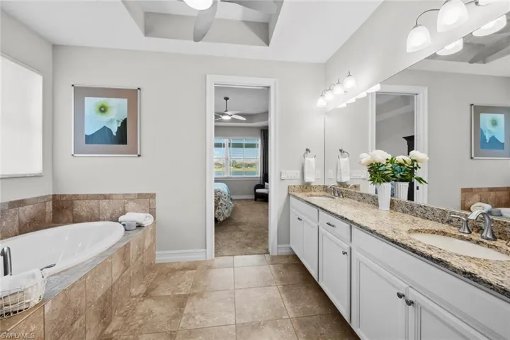 The master bathroom features a TRAY CEILING with ceiling fan/light (November 2020), comfort height double vanity with granite countertop, tile floor, and AUTOMATED WINDOW BLIND with remote (August 2017).