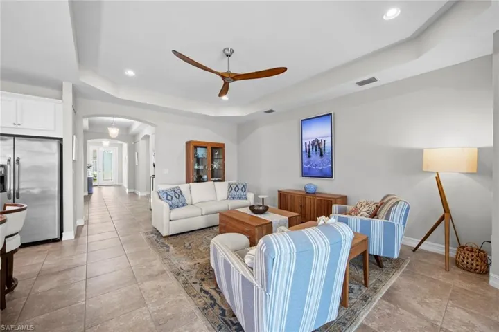 The great room has a tray ceiling, tile floor, and ceiling fan.