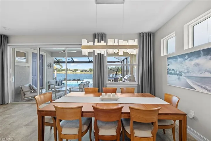 The dining area overlooks the water and has a tile floor and new dining room chandelier (July 2022).