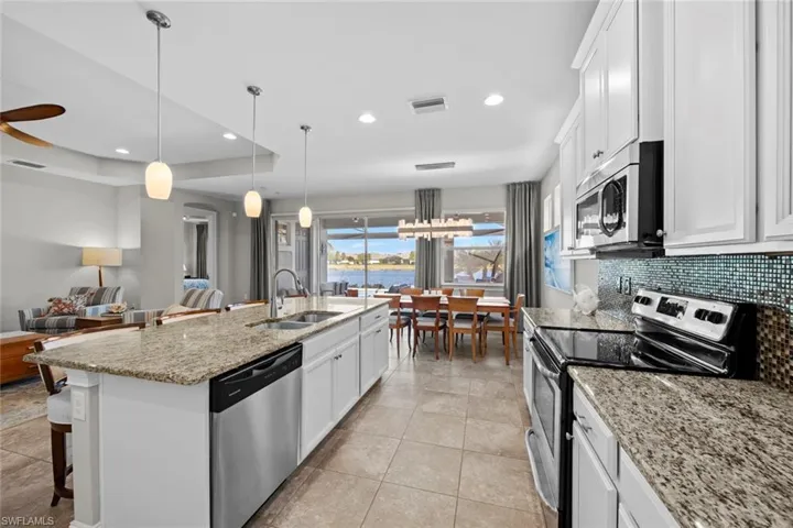 The island has a stainless steel sink, and faucet with integrated sprayer. The kitchen has recessed lighting, and island pendants.