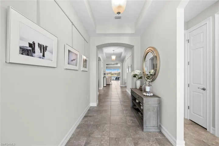 Hallway featuring tile floor, arch detail and tray ceilings. NEST THERMOSTAT (November 2020)