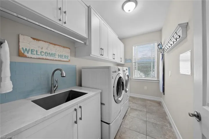 The large laundry with linen closet, tile floor, window binds (April 2017), custom cabinetry (October 2020), laundry sink with tile backsplash (October 2020), and LG washer and dryer. (April 2017).