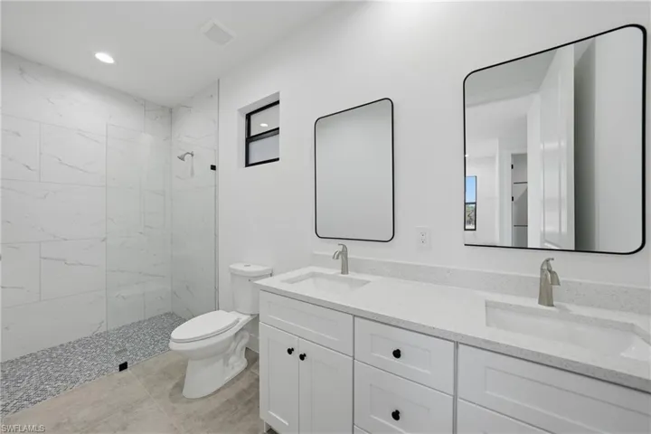 Full bathroom featuring double vanity, a marble finish shower, and recessed lighting