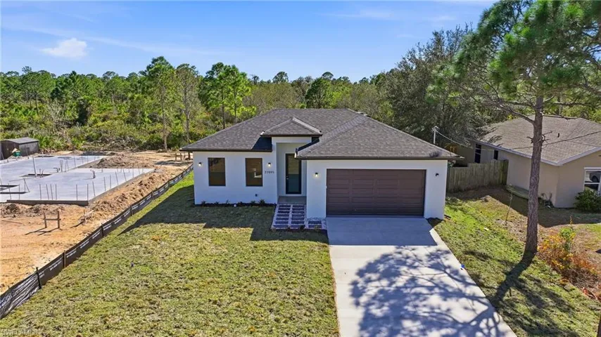 View of front facade with stucco siding, driveway, a garage, and roof with shingles
