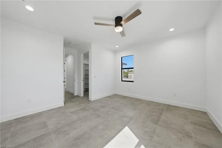 Unfurnished bedroom with a spacious closet, recessed lighting, and a ceiling fan