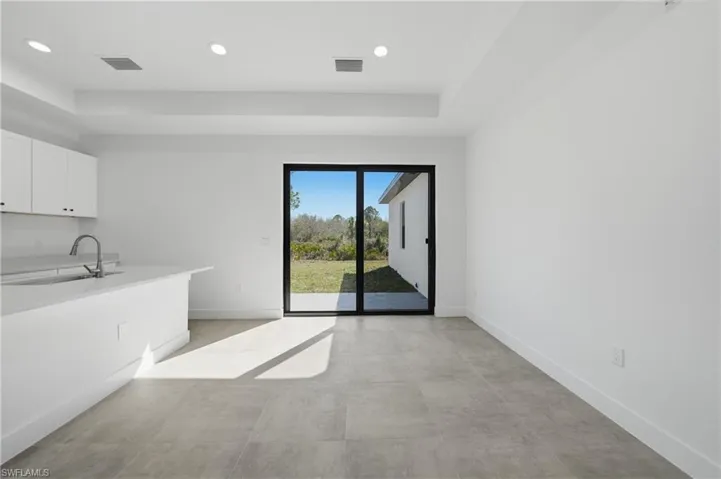 Unfurnished dining area featuring a raised ceiling, recessed lighting, and concrete floors