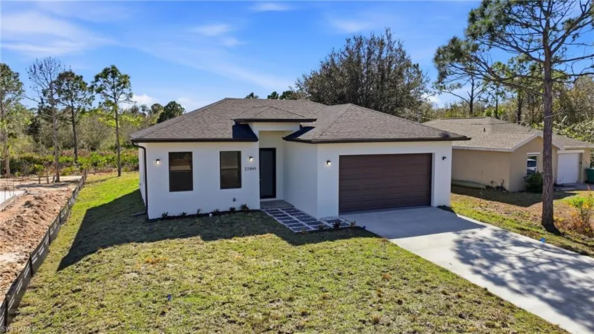 View of front of house with a shingled roof, stucco siding, an attached garage, and a front lawn