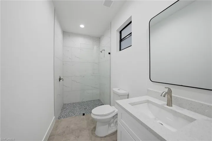 Full bathroom with a marble finish shower, vanity, and recessed lighting