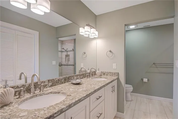 Full bathroom with double vanity, a shower stall, and a walk-in closet