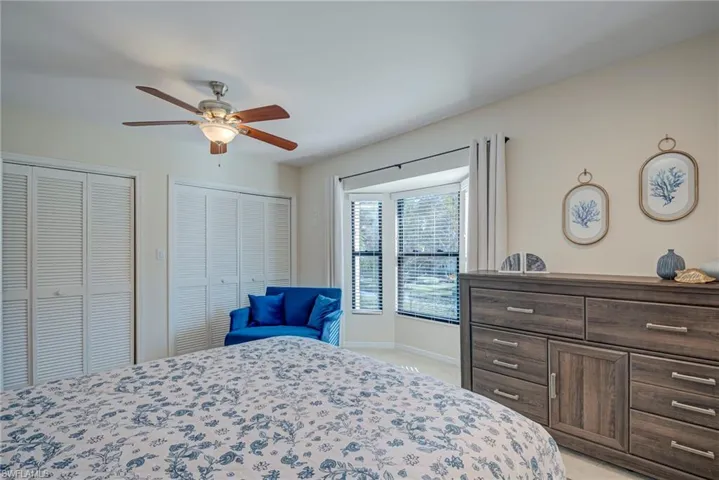 Bedroom with multiple closets, ceiling fan, and light colored carpet