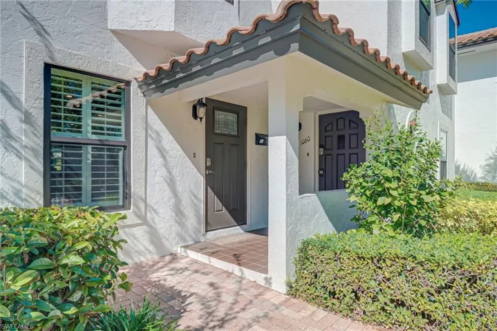 View of exterior entry with stucco siding and a tiled roof