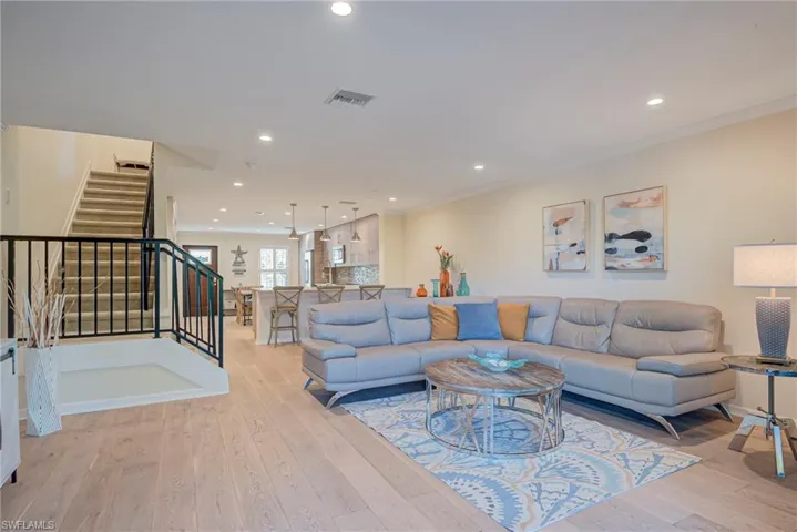 Open floor plan easy to entertain from inside to outside! Dining area, bar area, and living area featuring recessed lighting, light wood style floors, and ornamental molding