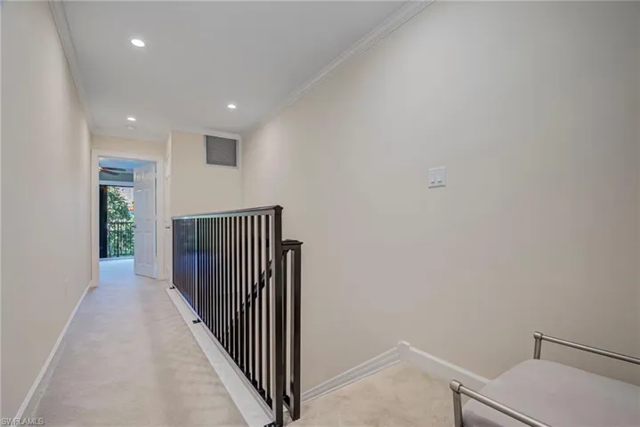Hall featuring ornamental molding, recessed lighting, and light colored carpet. There is a landing area at the top of the stairs with a decorative bench. The hallway divides the two bedrooms.