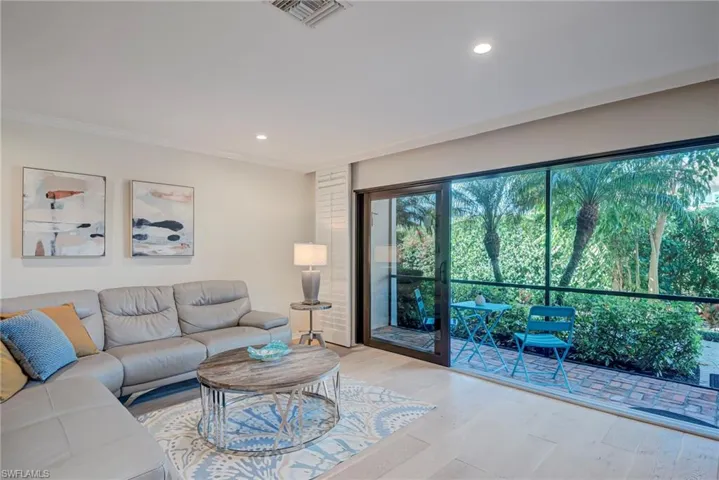 Living room with wood finished floors, recessed lighting, and crown molding. Accordian shutters and impact doors! Screened-in lanai that has a door to go outside to the path- pool- carport.