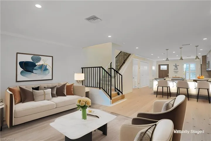 Virtually Staged to show placement of furniture and other options. Living room with light wood finished floors, recessed lighting, ornamental molding, and french doors