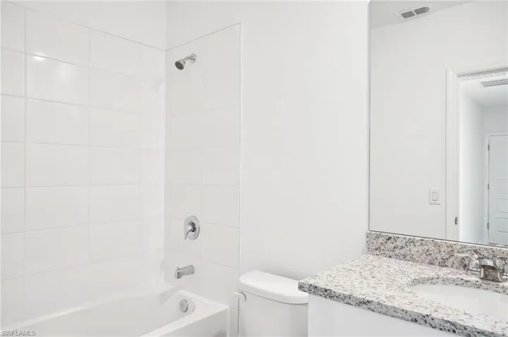 Full bathroom with tiled shower / bath, vanity, and toilet