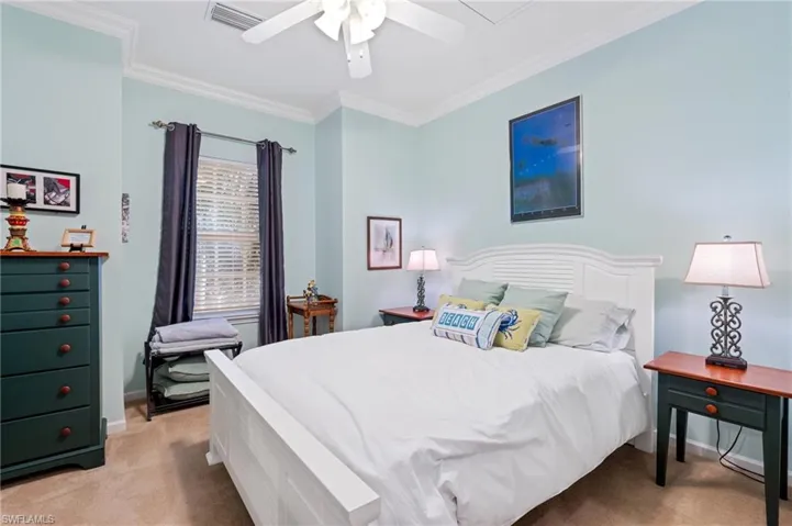 Carpeted bedroom featuring ceiling fan and ornamental molding
