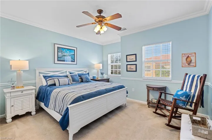 Bedroom with ceiling fan, light carpet, and ornamental molding