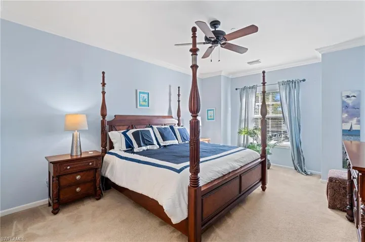 Carpeted bedroom with ceiling fan and ornamental molding