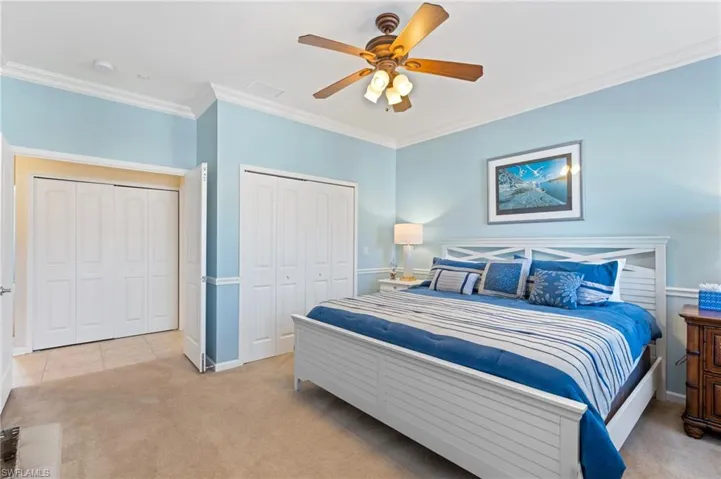 Bedroom with light carpet, ceiling fan, and ornamental molding