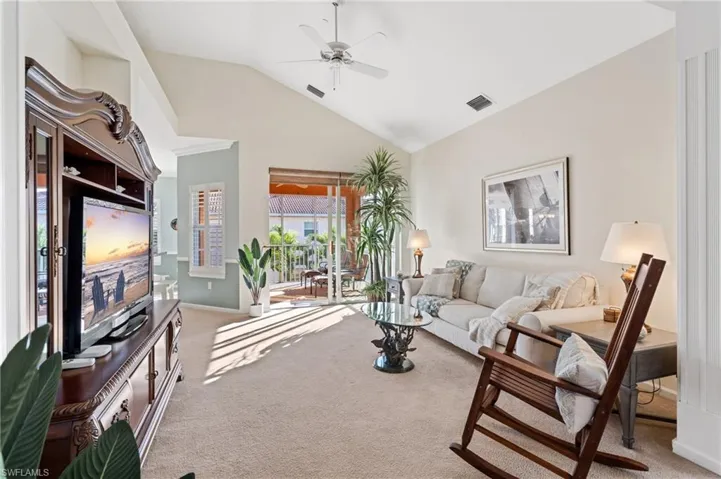 Living room featuring light colored carpet, vaulted ceiling, and ceiling fan