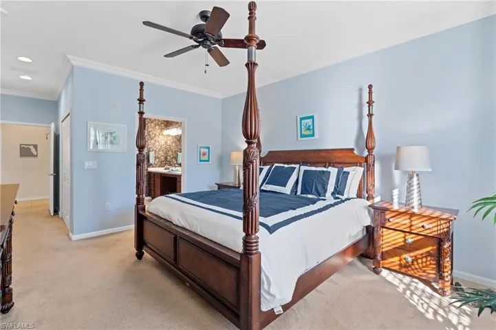Bedroom with light carpet, ensuite bath, ceiling fan, and crown molding