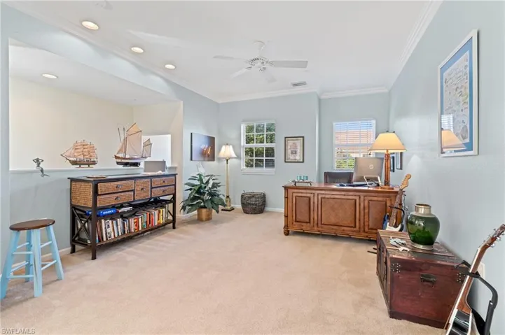Office space with ceiling fan, light colored carpet, and crown molding