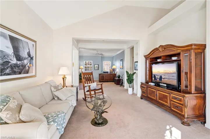 Carpeted living room featuring ceiling fan and lofted ceiling
